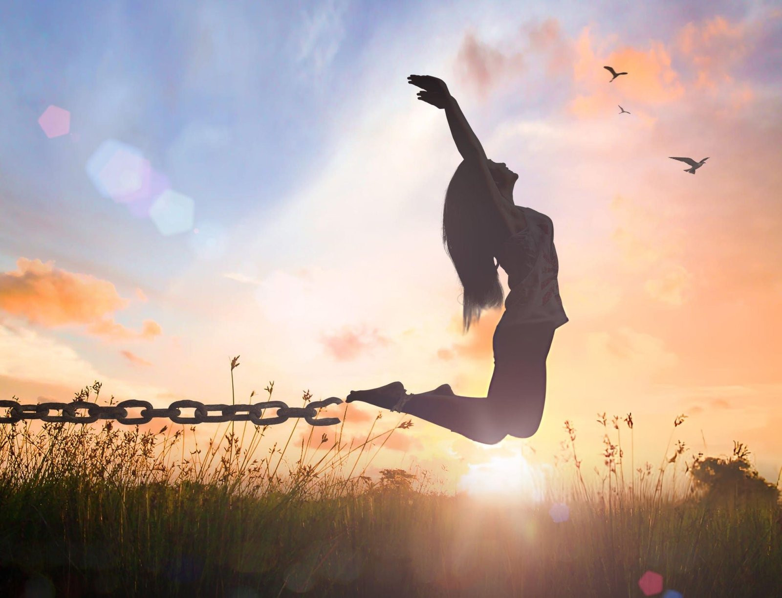 Silhouette of a figure in mid-leap, arms raised, breaking free from a grounded chain. Sunset scene with soft clouds, birds in flight, and a grassy field. Represents emotional liberation and overcoming constraints, aligning with DBT strategies for anxiety reduction.